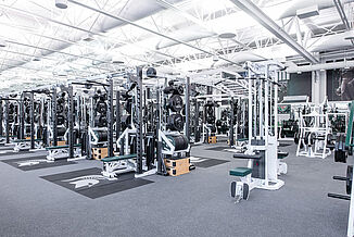 The weight racks and lateral pulldown machines available in the Michigan State football weight room. A number of different machines are located in the background of the image as well. All equipment rests on REGUPOL aktivpro roll flooring. 