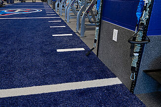 Tennessee Titans Practice Facility weight room featuring a blue turf area and REGUPOL aktivpro roll flooring in Thunder Gray. The team logo can be seen within the custom blue turf area.