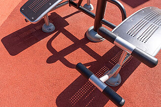 REGUPOL Safety and Sports Surfacing for Outdoor Fitness Areas in Berlin Close-up of seamless REGUPOL impact-absorbing safety surfacing and sports surfacing beneath outdoor fitness equipment at an accessible play and recreation area in Berlin-Steglitz-Zehlendorf.