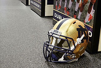 A gold Notre Dame football helmet sitting on gray REGUPOL aktiv flooring with the Notre Dame logo.