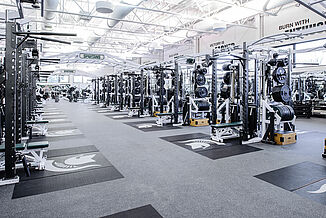 Rows of weight racks at Michigan State football weight room facility, each featuring an individual, inlaid REGUPOL crash platform with a customized Spartan logo. 