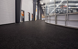 An outer view of the walk way around Thayer Sports Center hockey rink with multiple doorways to locker rooms. 