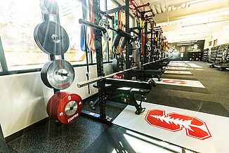 An angled view of the weight racks offered to athletes in the athletic performance center at Stanford University. All equipment is positioned on REGUPO aktivpro roll flooring, with inlaid platforms created with REGUPOL crash flooring.