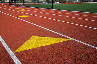 A yellow arrow is painted on St. John's running track, directing runners towards the finish line.