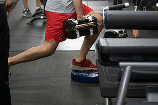 Athlete performs weighted lunges on REGUPOL aktiv rolled rubber flooring at Kelowna High Performance.