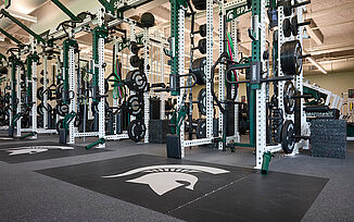 Weight racks in the Michigan State University hockey weight room with REGUPOL aktivpro roll flooring and platforms.