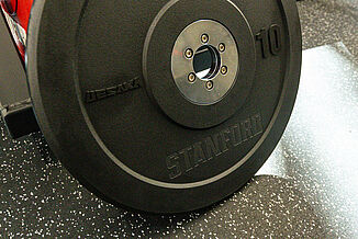 A Stanford University weight plate rests atop REGUPOL aktivpro roll flooring.