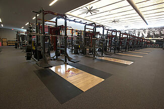 A row of weight training racks at Iowa State, each with individual platforms. REGUPOL aktivpro roll flooring and REGUPOL crash is featured throughout the facility.