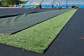 REGUPOL abzorb synthetic turf shock pad is installed beneath the turf at Spring Grove Area High School. The view shows the installation as the turf is placed on the shock pad.