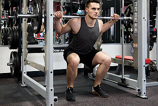 Athlete performs a weighted squat on REGUPOL aktiv rolled rubber flooring in the UFC Gym. The floor provides a stable and comfortable environment for heavy weight training to take place.