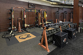 The Hershey Bears weight room features two squat racks with inlaid platforms in the floor, as well as a full dumbbell rack with a variety of weights.