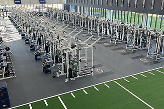 Aerial view of a spacious strength and conditioning facility with weightlifting equipment, turf area and REGUPOL aktivpro roll flooring with crash zones.