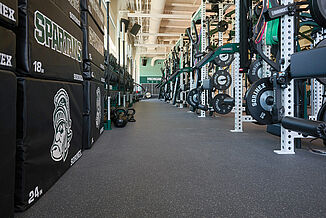 Weight rack with weights at Michigan State hockey facility, also featuring plymometric boxes offered to athletes. All equipment is located on REGUPOL aktivpro roll flooring.