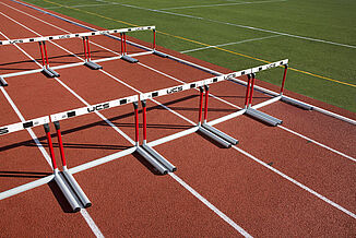 White hurdles are neatly arranged on St. John's REGUPOL champion AG running track.