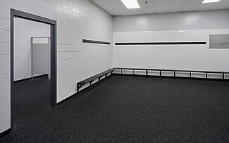 Thayer Sports Center's empty locker room with black bench, white lockers and REGUPOL aktiv rolled rubber flooring.