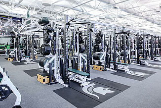 View of the rows of weight racks located at Michigan State's football weight room facility. The racks feature REGUPOL crash zones that seamlessly transition into the REGUPOL aktivpro roll flooring.