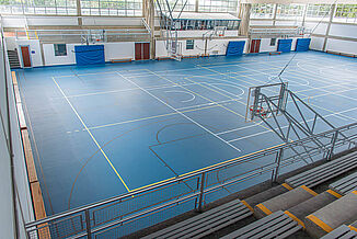 Sports hall with blue REGUPOL dynamic classic sports hall flooring, line markings, and spectator stands