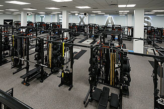 View of the variety of machines and weights offered to athletes within University of Texas at Austin weight training facility. REGUPOL aktivpro roll and crash are used throughout the facility.