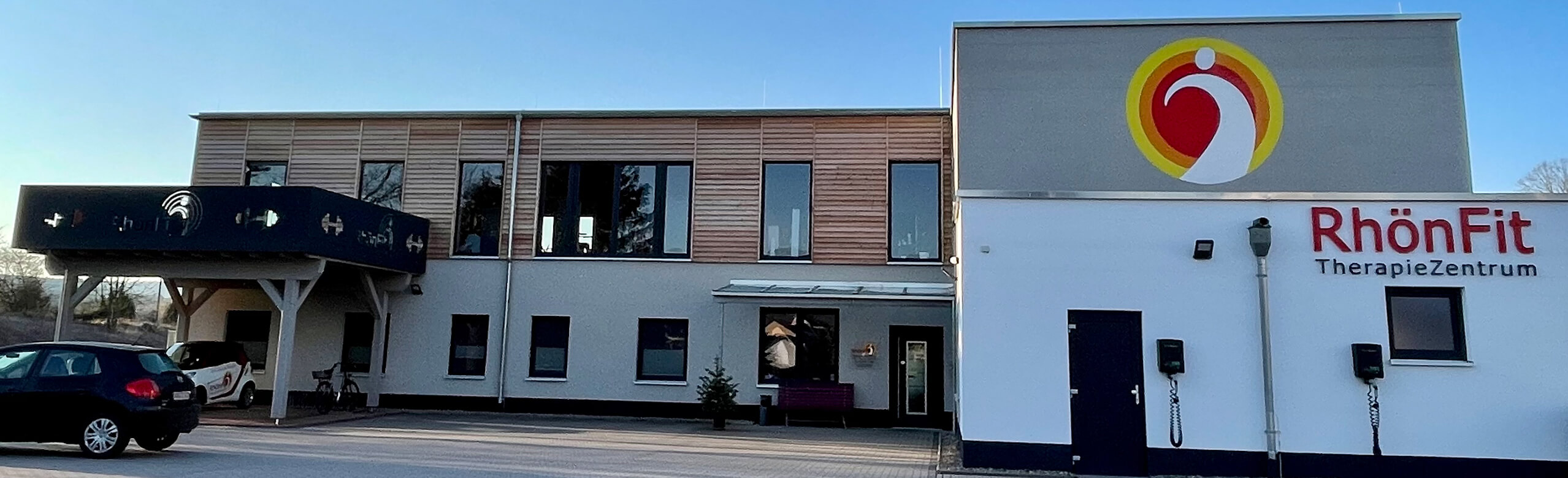 Exterior view of the RhönFit Therapy Centre in Dermbach with a façade made of plaster and wood.