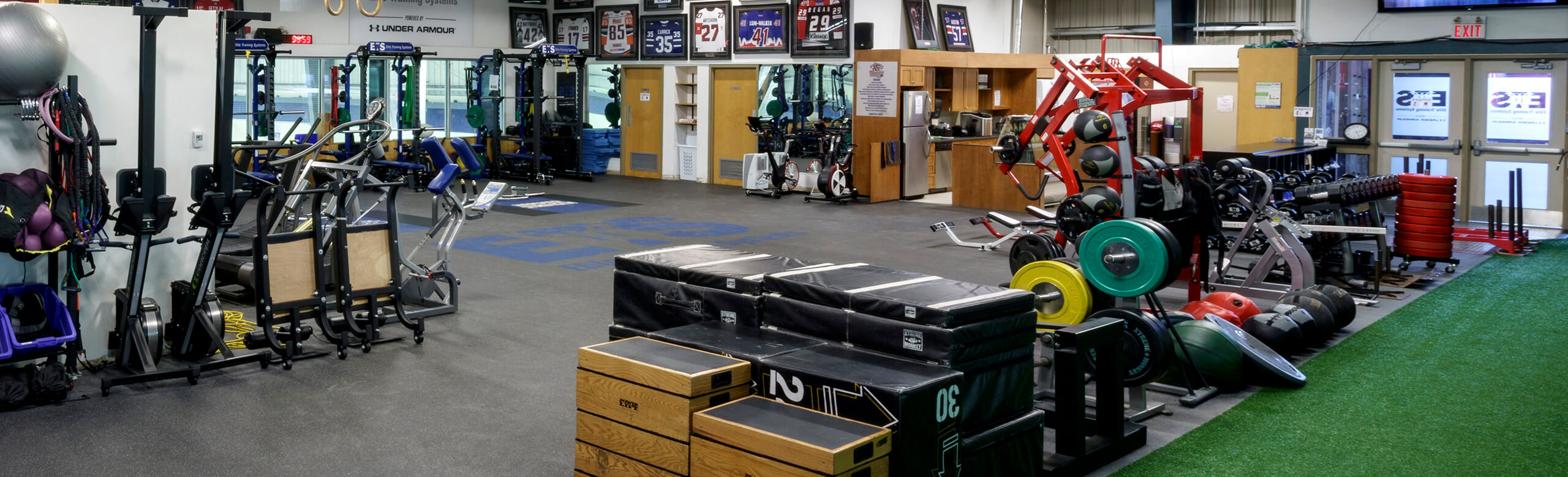 View of the Elite Training Systems facility at the Iroquois Park Sports Centre. The training center features a variety of equipment and machines for athletes, as well as a turf area and REGUPO aktivpro roll flooring throughout.