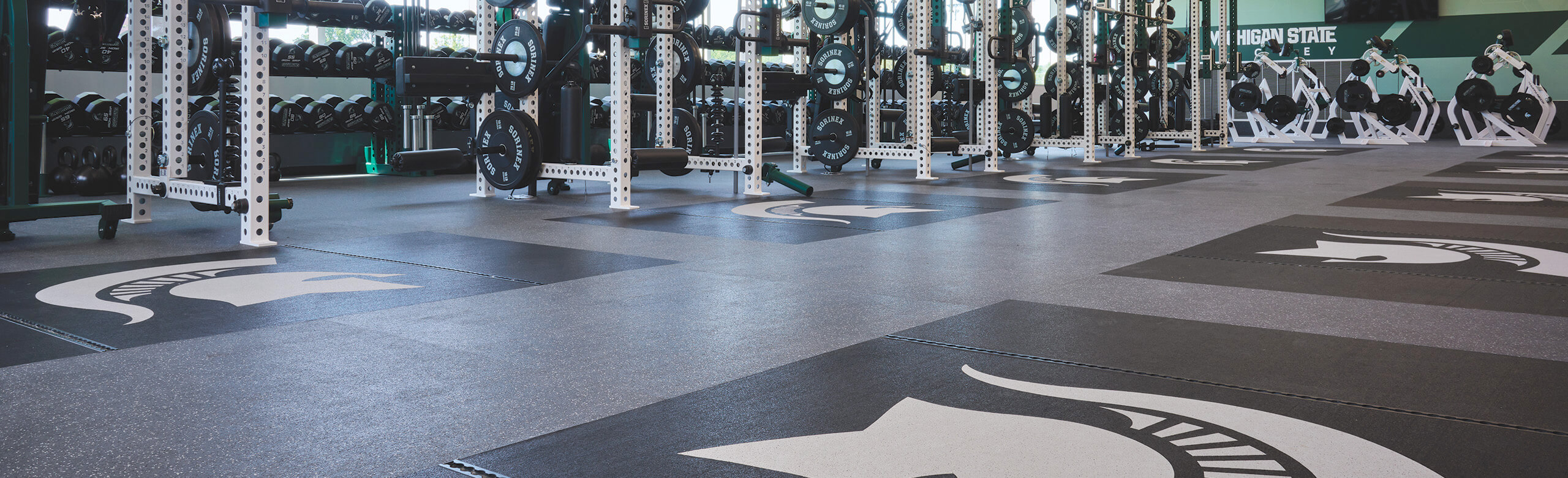 Michigan State University hockey weight room with black REGUPOL flooring and inlaid platforms.