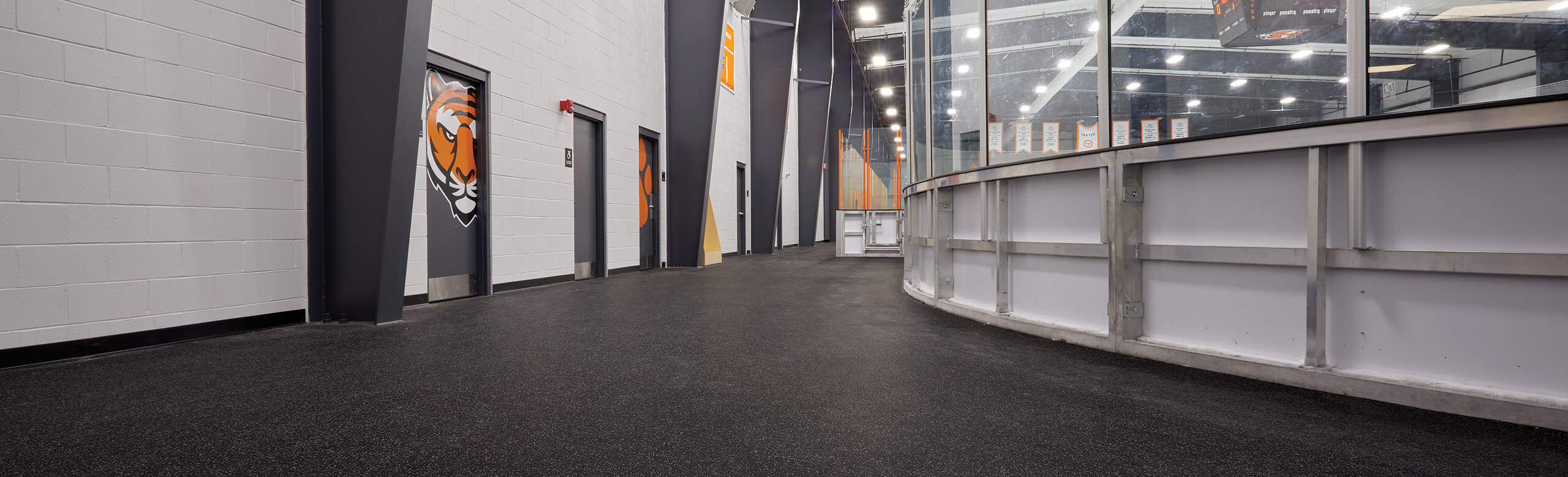 An outer view of the walk way around Thayer Sports Center hockey rink with multiple doorways to locker rooms. 