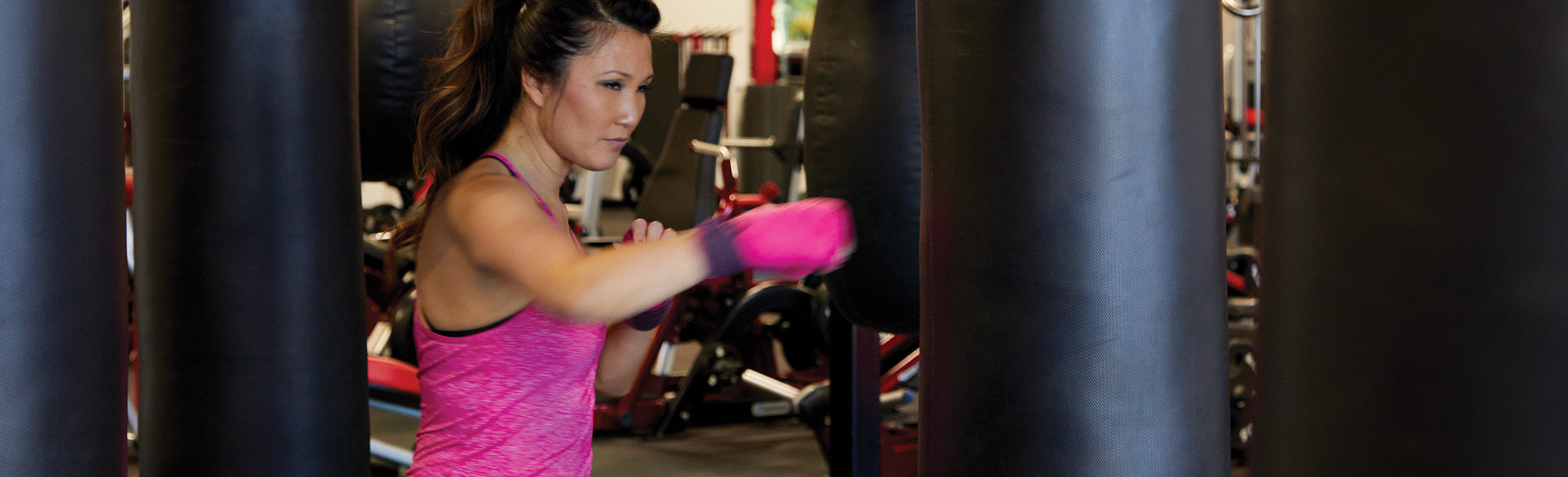 A woman at the UFC Gym trains her skills as she punches a punching bag. She is standing atop REGUPOL aktiv rolled rubber flooring.